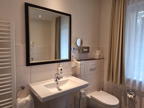 A bathroom with a white sink, a mirror, a toilet, and a towel rack.