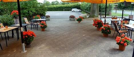 An outdoor patio area with hexagonal paving, yellow umbrellas, and potted plants.