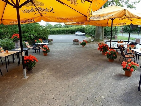 An outdoor patio area with hexagonal paving, yellow umbrellas, and potted plants.