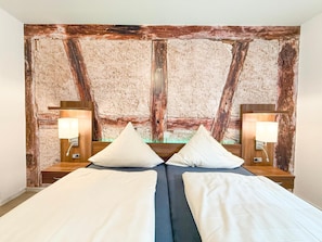 A hotel room with a rustic wall design, two beds with white linens, and bedside lamps.