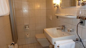 Une salle de bain avec un lavabo blanc, des toilettes, un espace douche et un porte-serviettes.