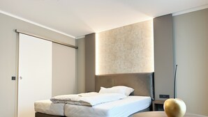 A modern bedroom with a bed, a round table, and a wall-mounted light fixture. - Hotel Restaurant Hackmann-Atter (Osnabrueck)