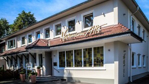 A two-story hotel with a classic architectural style, featuring a prominent sign with the name "Hotel Altis" and a tiled roof. - Hotel Restaurant Hackmann-Atter (Osnabrueck)