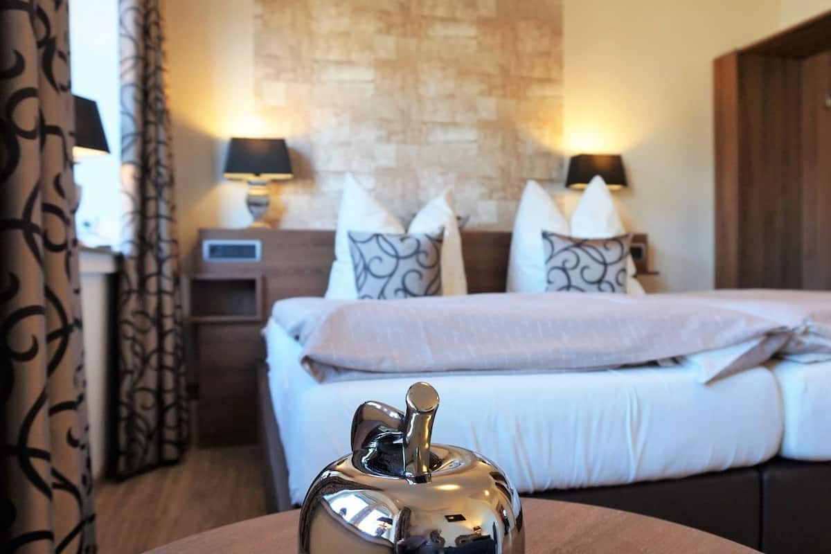 A hotel room with a bed, bedside lamps, a nightstand, and a decorative object on a table.