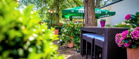 An outdoor seating area with wicker furniture and a green umbrella.
