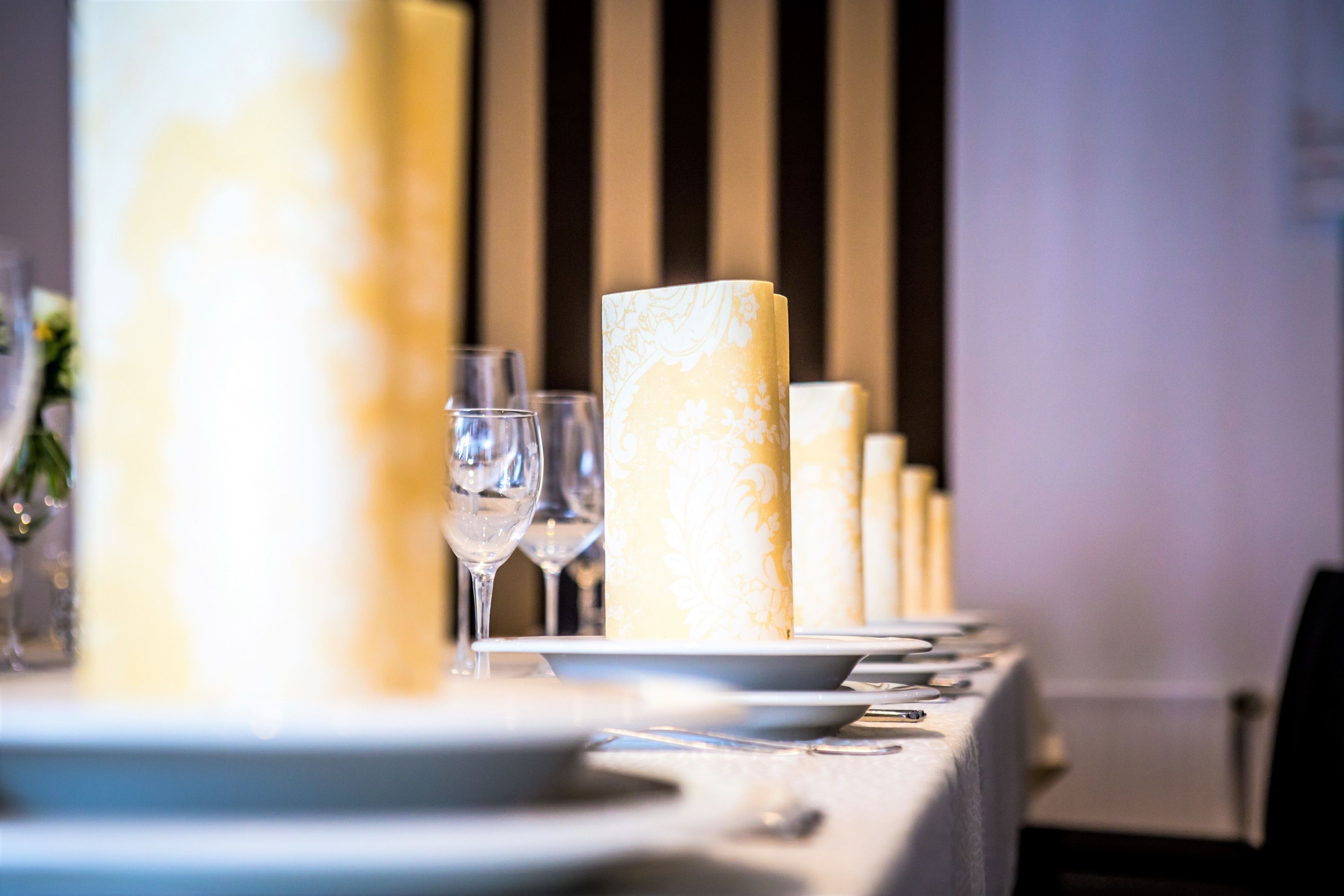 A dining table set with plates, glasses, and candles.