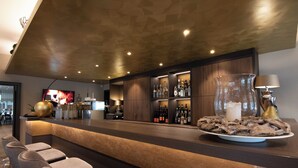 A modern bar area with a long counter, bar stools, and a variety of bottles and glasses. - Hotel Restaurant Hackmann-Atter (Osnabrueck)