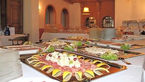 Ein Buffet mit verschiedenen Speisen, einer Kronleuchter und Rundbogenfenstern.
