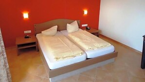 Ein Doppelbett mit Holz-Kopfteil, zwei Nachttische und eine Wand in Rot.