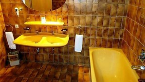 Ein Badezimmer mit einer gelben Badewanne, zwei Waschbecken, einem Spiegel und einem Handtuchhalter.