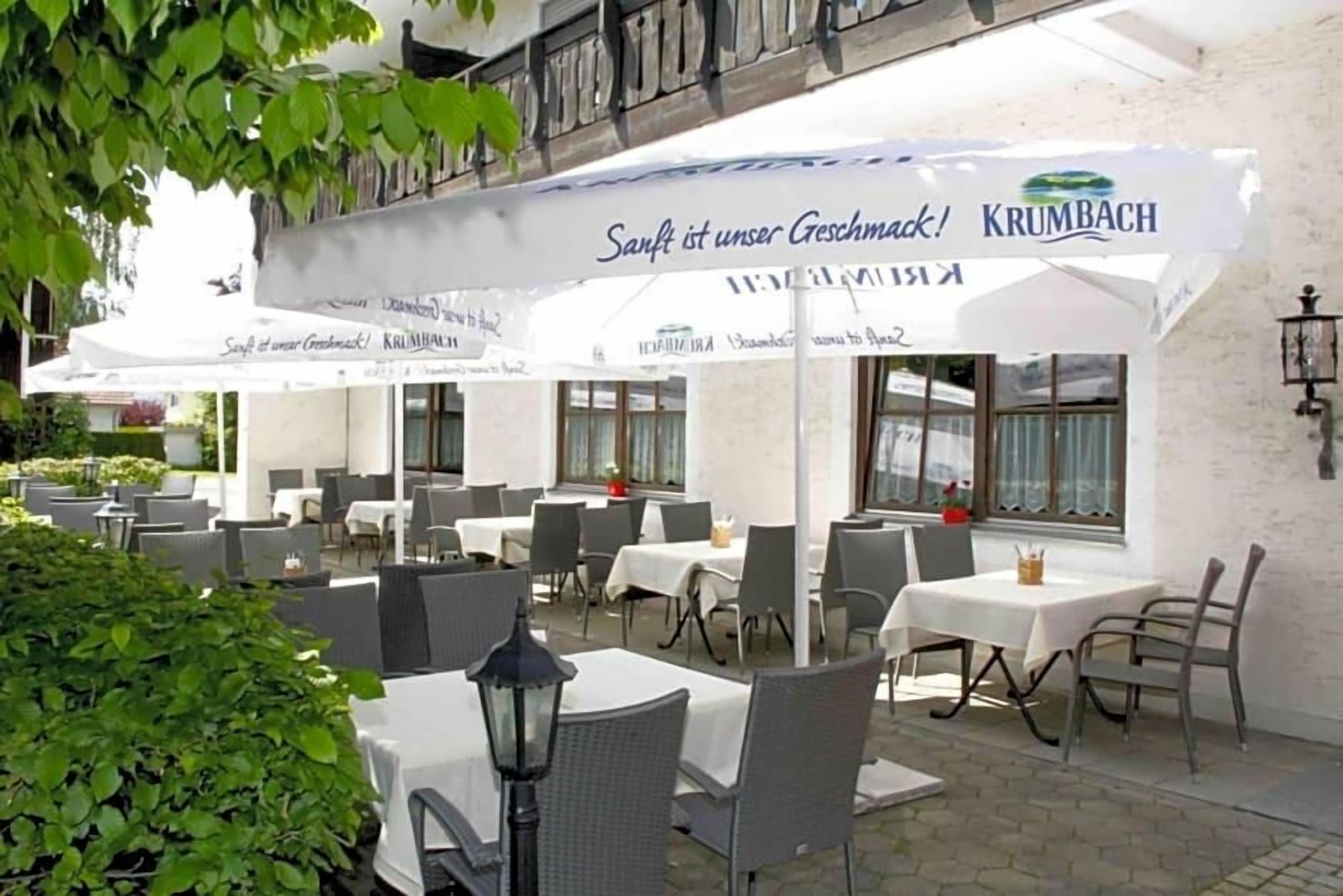 Un espace extérieur aménagé pour les repas, avec des tables et des chaises, protégé par des parasols, et une pancarte sur laquelle on peut lire : « La douceur est notre devise ! »