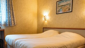 A double bed with white bedding in a hotel room. - Logis Hotel Heraclee (Saint-Gilles)