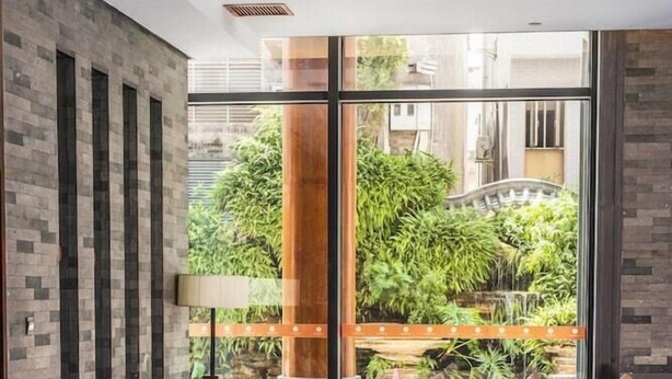 Un vestíbulo moderno con dos sofás, una mesa de centro y un ventanal que ofrece vistas a zonas verdes y una fuente.