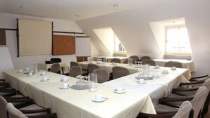 Ein Konferenzraum mit mehreren Tischen, gedeckt für das Essen, ausgestattet mit Stühlen und Tischaufstellungen.