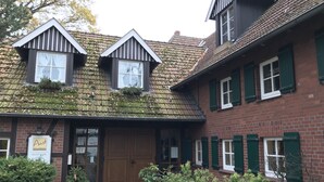 Ein traditionelles Gebäude mit einer Ziegelaußenwand, grünen Fensterläden und einem Ziegeldach.