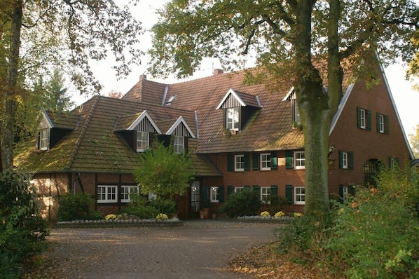 A traditional brick house with a sloped roof and multiple chimneys.