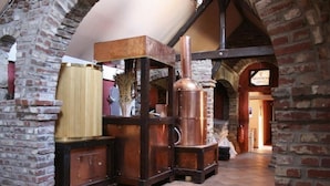 A rustic interior with exposed brick walls, a wooden table, and a copper boiler. - Mcmüllers Brauereigasthof (Linnich)