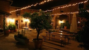 An outdoor patio area with brick walls, string lights, and potted plants. - Mcmüllers Brauereigasthof (Linnich)