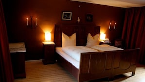 A bedroom with a wooden bed, two bedside tables with lamps, and a wooden floor. - Mcmüllers Brauereigasthof (Linnich)