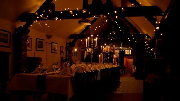 A dimly lit dining area with long tables set for a meal, featuring string lights and candle candles. - Mcmüllers Brauereigasthof (Linnich)