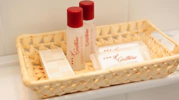 Un panier en osier contenant des articles de toilette, notamment des mouchoirs en tissu et deux flacons de lotion.