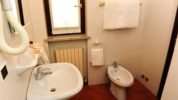 Une salle de bain équipée d’un lavabo, d’un bidet, d’un porte-serviettes et d’une fenêtre.