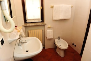 Une salle de bain équipée d’un lavabo, d’un bidet, d’un porte-serviettes et d’une fenêtre.