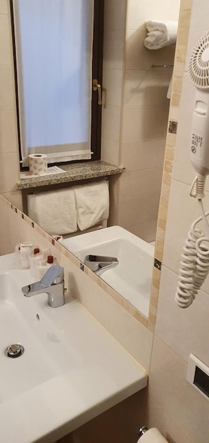 Een badkamer met een wastafel, spiegel, handdoekhouder en een haardroger.
