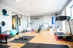 A gym with various exercise equipment, including a treadmill, stationary bikes, and free weights.