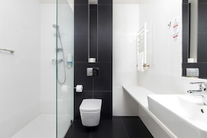 A modern bathroom with a glass-enclosed shower, a white toilet, and a large white bathtub.