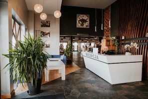 A reception area with a reception desk, seating, potted plants, and artwork on the walls.