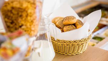 A wicker basket with bread and a milk jug on a table.