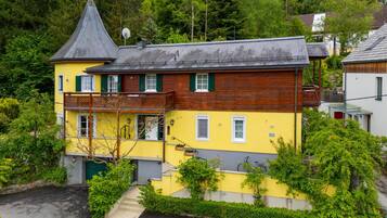 Ein zweistöckiges Gebäude mit einem steilen Satteldach, einem Balkon und einer kleinen Treppe, die zum Eingang führt.