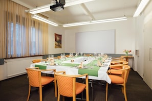 A conference room with a long table set for a meeting, surrounded by chairs.