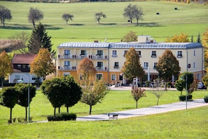 A multi-story building with a flat roof, surrounded by a well-maintained lawn and trees.
