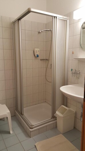 A shower enclosure with a glass door, a white sink, and a mirror above it.