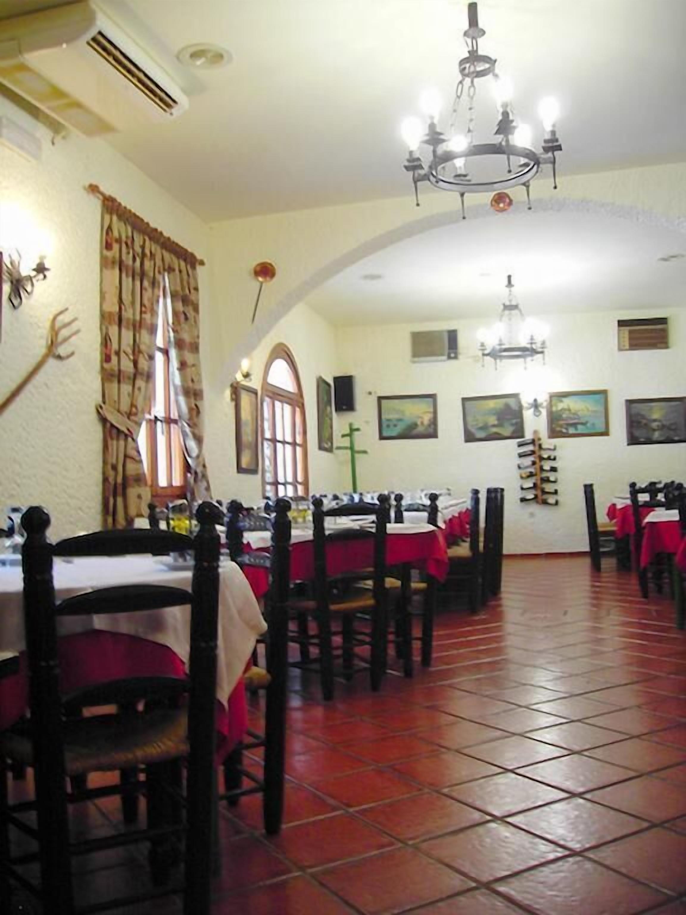 A dining area with tables and chairs, a chandelier, and artwork on the walls.