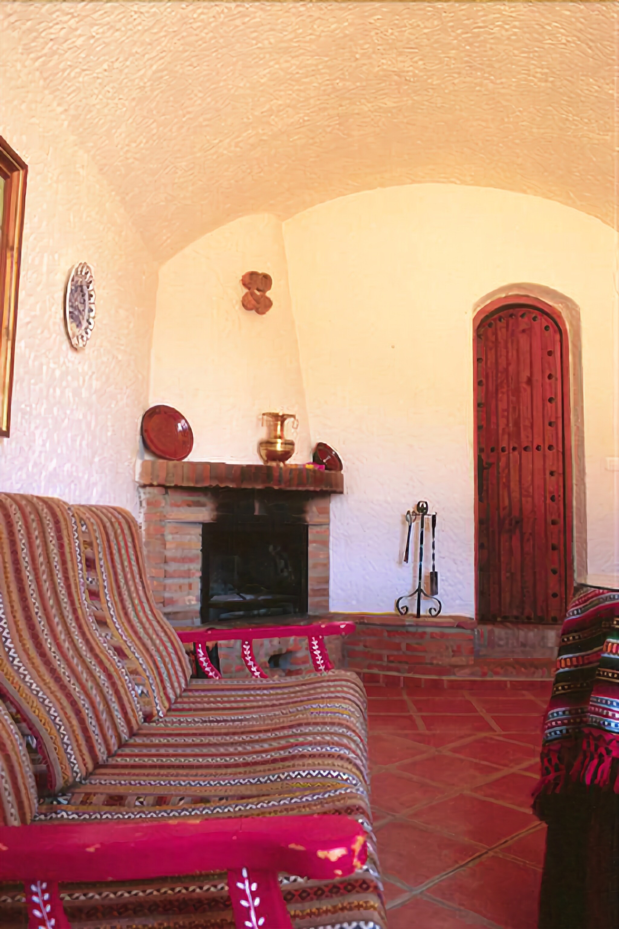 Uma sala de estar aconchegante com um sofá estampado, uma lareira e uma porta de madeira.