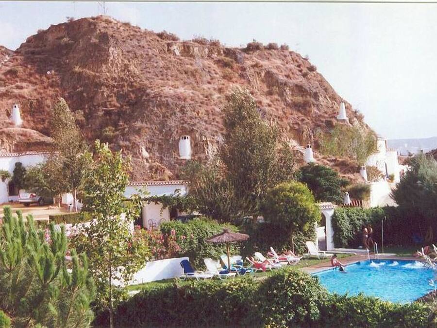 Zona de piscina con sillas de descanso y montañas al fondo.