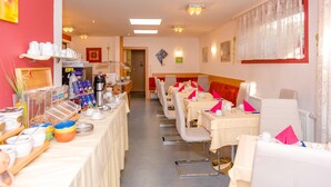 A hotel dining area with tables set for breakfast, a coffee station, and a buffet with various food items. - 1a Hotel Steiner (Judenburg)