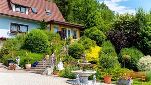 A house with a garden featuring a fountain, steps, and a bench. - 1a Hotel Steiner (Judenburg)