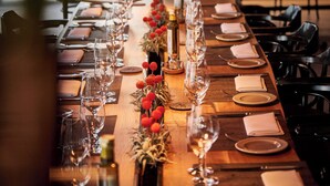 A long dining table set with wine glasses, plates, and cutlery, reflecting a well-lit interior space. - Hotel Restaurant Reuter (Rheda-Wiedenbruck)