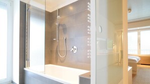 A modern bathroom with a glass-enclosed shower, a standalone bathtub, and a separate shower area. - Hotel Restaurant Reuter (Rheda-Wiedenbruck)