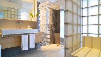 A modern bathroom with a large mirror, a glass shower enclosure, and a built-in bench.