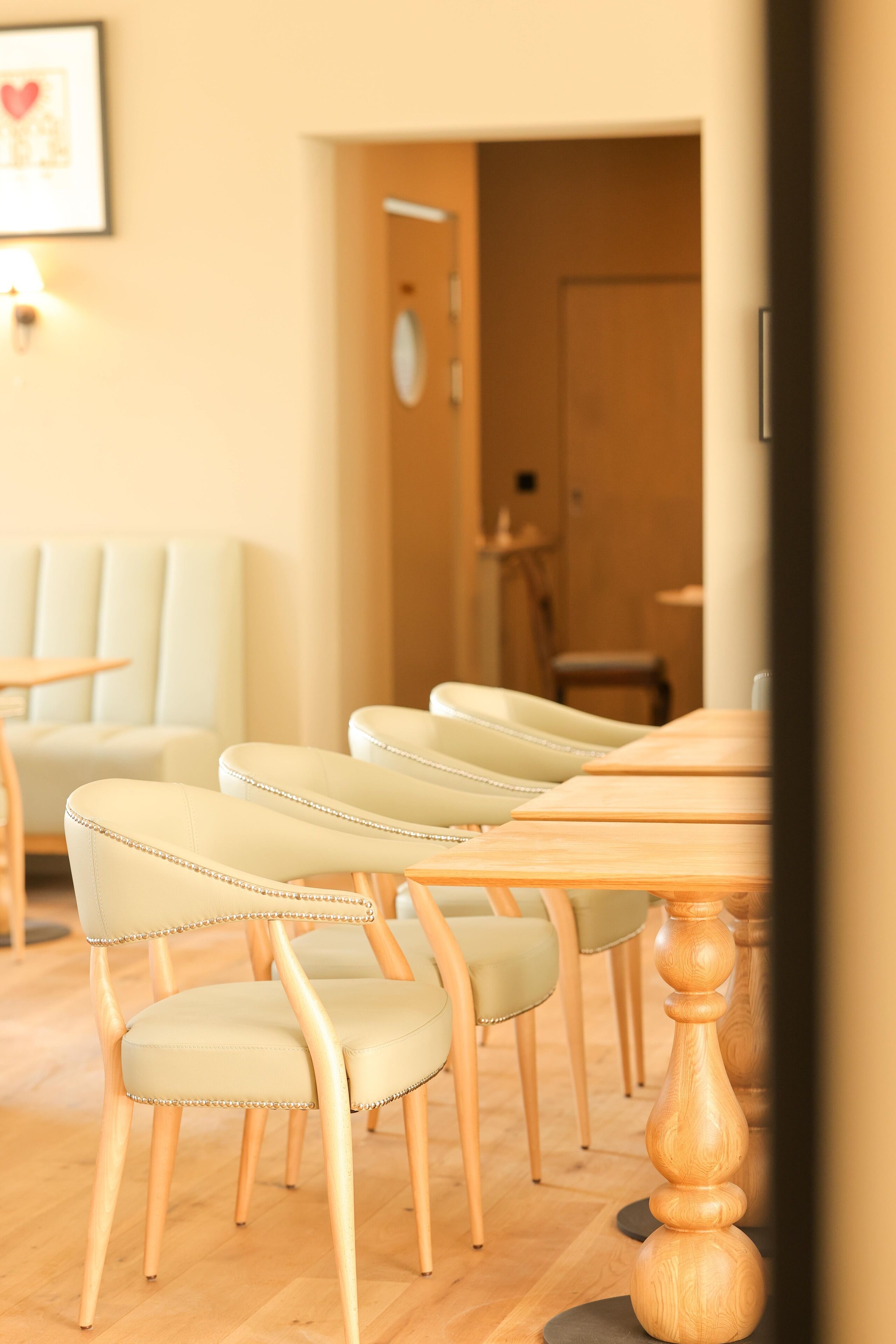 A dining area with a wooden table and chairs, a framed picture on the wall, and a door in the background.