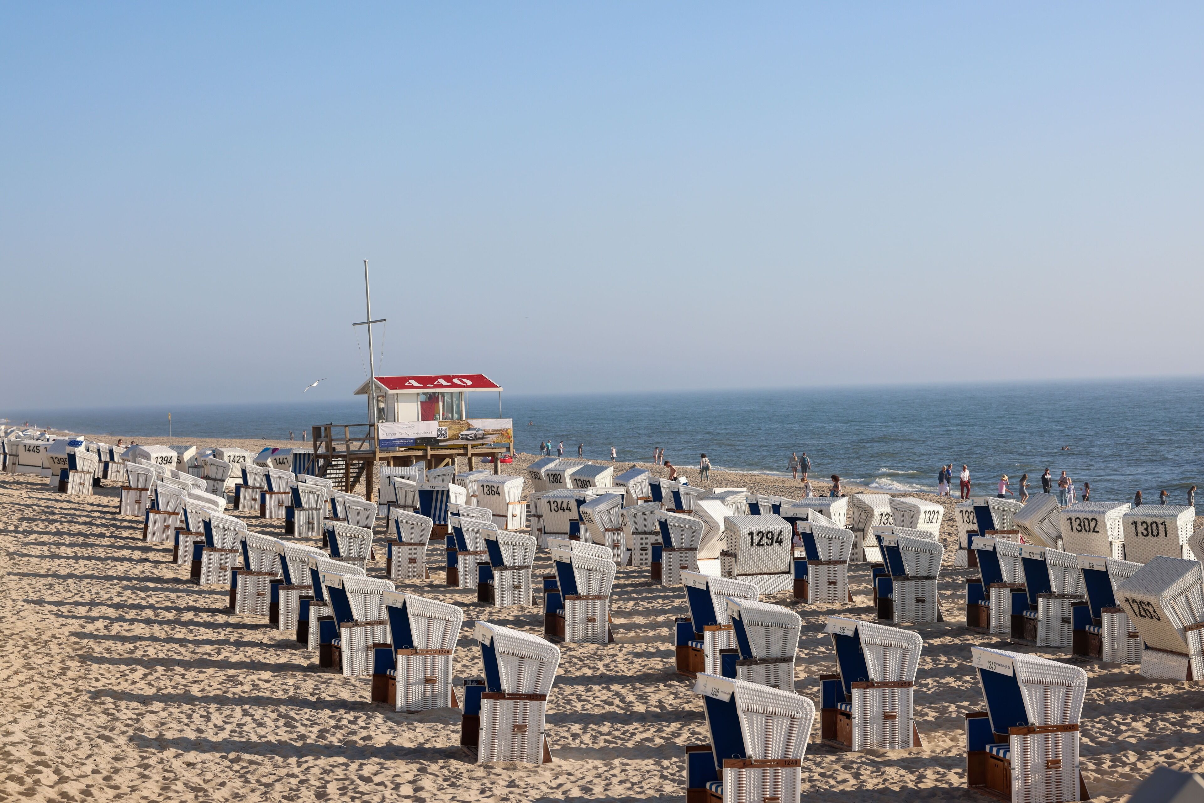 A beach with rows of numbered beach chairs and a lifeguard tower.