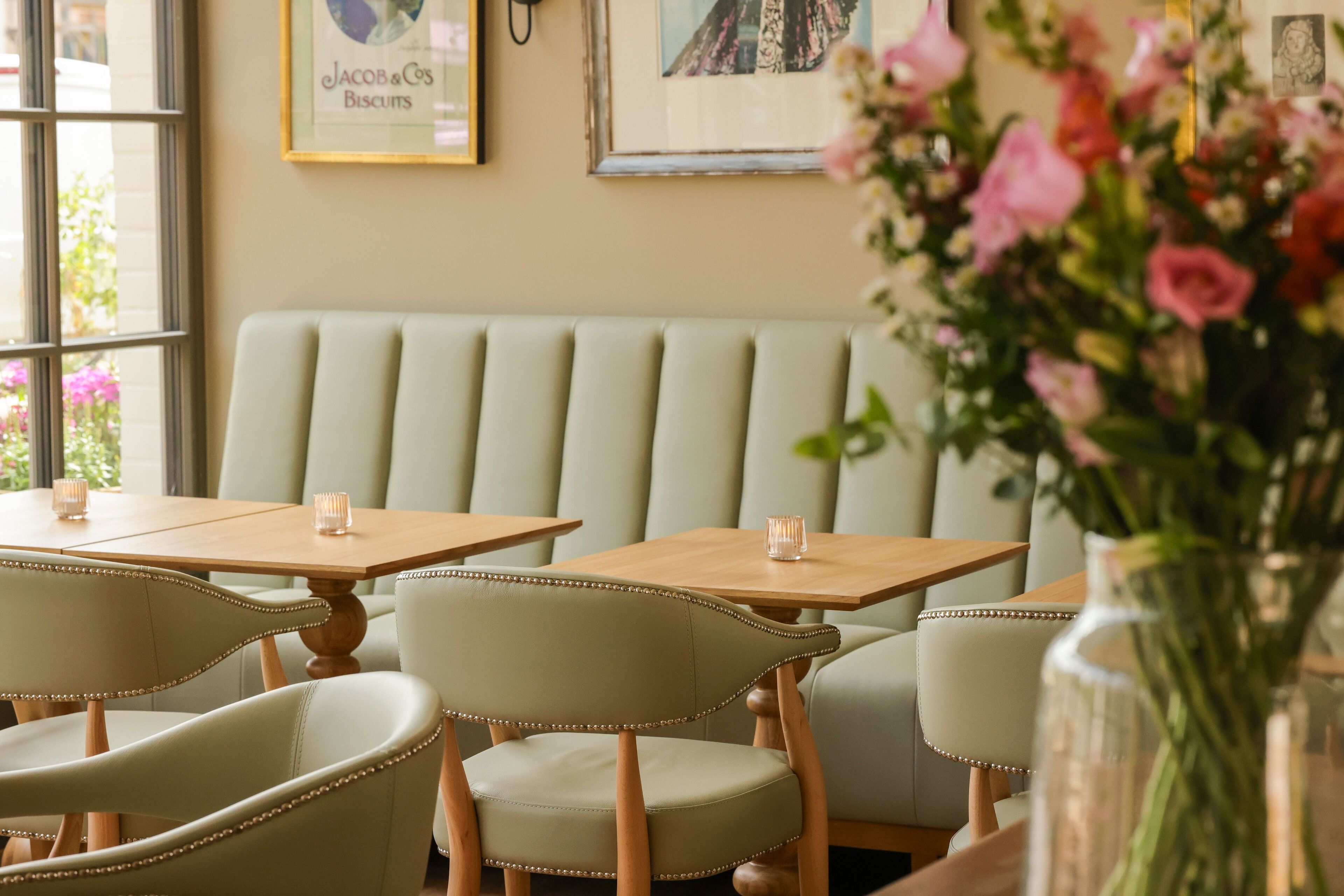 A dining area with a light green booth seating, wooden tables, and chairs with pearl-studded details.