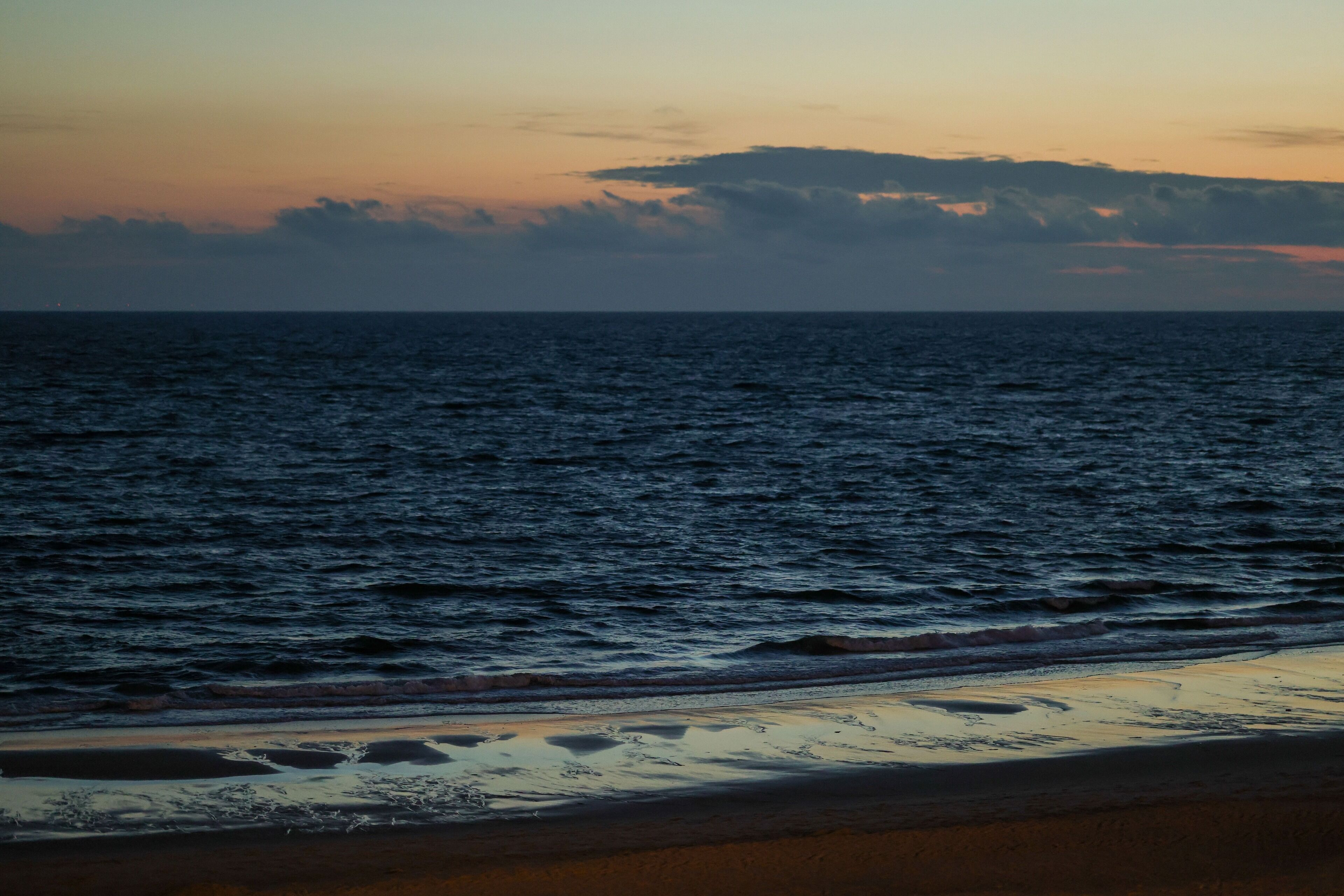 Een strand met golven die naar de kust rollen.
