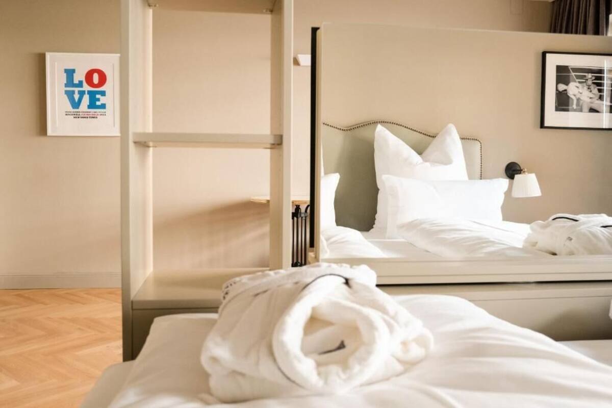 A hotel room with a bed, a mirror, a framed picture on the wall, and a towel on the bed.