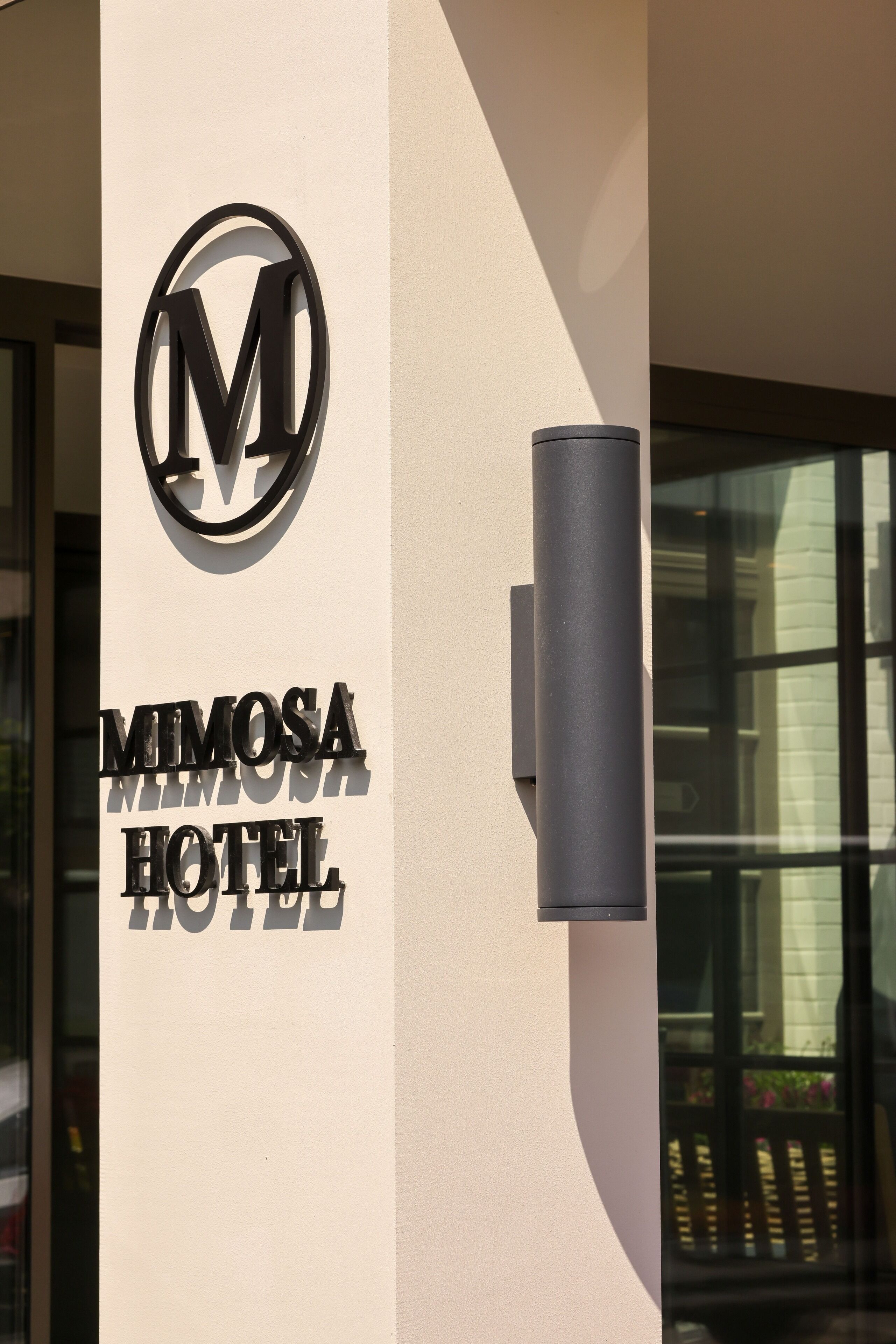 Placa de hotel com o nome 'Mimosa Hotel' e um logotipo.